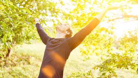 Happy man in nature does breathing exercise for air in summerの写真素材