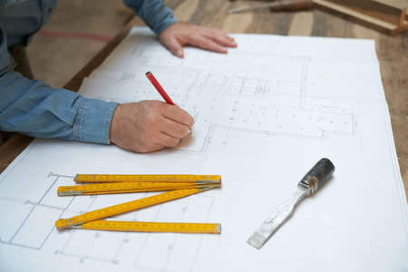 Architect or craftsman draws a building plan or a house floor plan