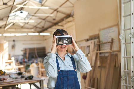 Craftsman woman with VR glasses during virtual reality simulation in the carpentry shop