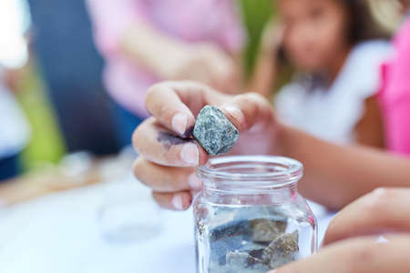 Children examine rocks and minerals in the summer school at the holiday campの写真素材