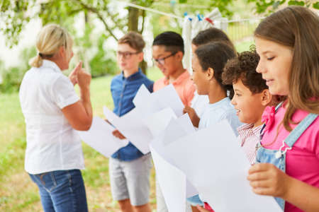 Teacher practices singing with the children's choir in the summer camp for the talent showの写真素材
