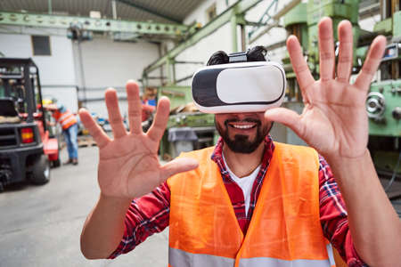 Worker with VR glasses reaches for a virtual reality factory simulation