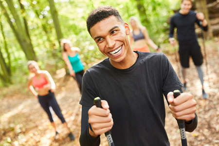 Laughing young man while Nordic walking with friends in nature in summerの写真素材