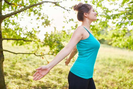 Happy young woman breathing fresh air during stress relief workout in nature