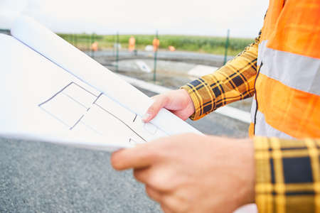 Construction worker with floor plan when planning the construction of a house in the new development areaの写真素材