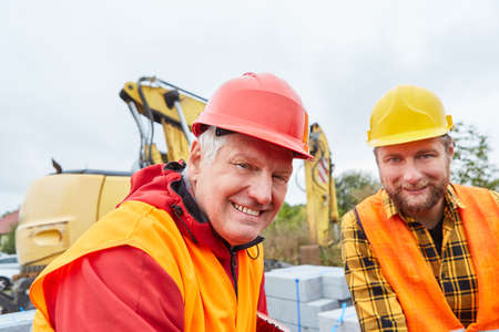 Smiling architect and construction worker on construction site of house building with excavatorの写真素材