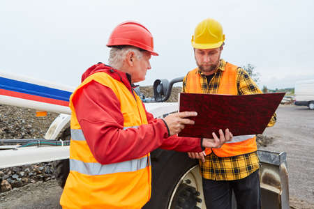 Architect and construction worker with documents on the construction site from road construction in...