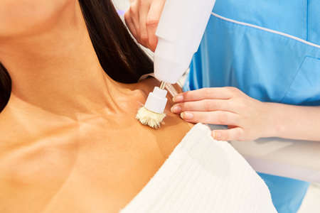 Woman having skin cleansing and lymph massage with an electric brush in the cosmetic studioの写真素材