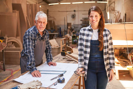 Senior craftsman and woman as apprentice in training in the carpentry workshopの写真素材