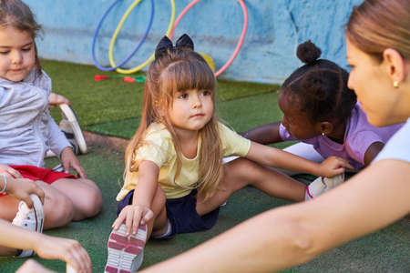 Little girl stretching in physical education class with other children in daycare