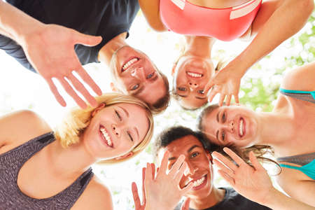 Group of young people happily waving at camera for friendship and team spiritの写真素材