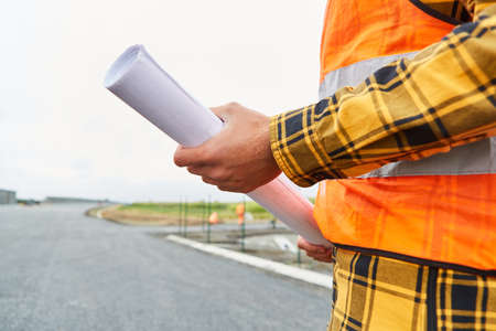 Worker on construction site from road construction with construction drawing or site plan documentの写真素材