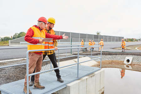 Site manager and construction worker inspecting a construction on a road construction siteの写真素材