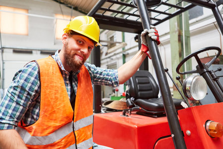 Young man as a forklift driver in training on the forklift in the shipping company or factoryの写真素材