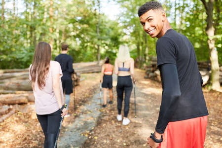 Group of friends in a Nordic walking hiking group in nature in summerの写真素材