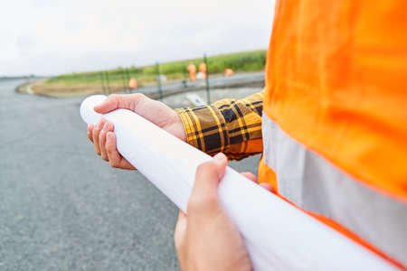 Worker holds a zoning plan or site plan on the construction site of road constructionの写真素材
