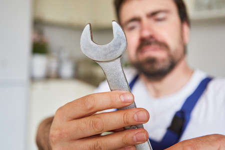 Installer from the emergency service holds an open-end wrench for assembly or installationの写真素材