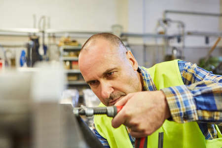 Locksmith or metal worker works with screw clamp on a workbench in the workshop