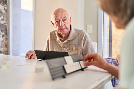 Seniors with dementia play at the Rummikub as a brain teaser and memory training in the nursing homeの写真素材