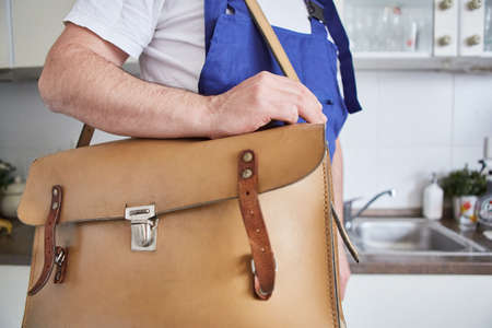 Plumber handyman with tool bag in the kitchen as a repair emergency serviceの写真素材