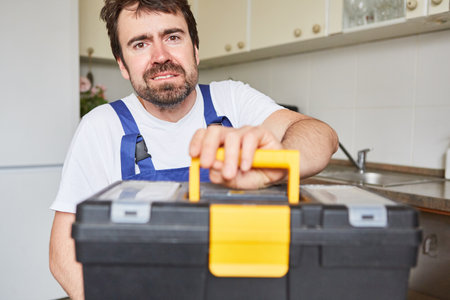 Man as a craftsman from the plumber's emergency service with tool box in the kitchenの写真素材