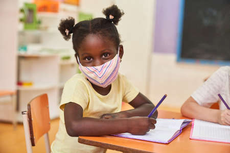 African girl with a protective mask because of virus in preschool or elementary schoolの写真素材