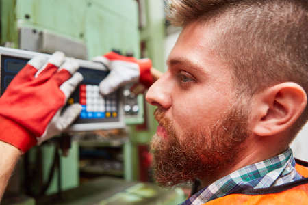 Worker as a machinist during maintenance and control of a machine in the metal construction workshopの写真素材