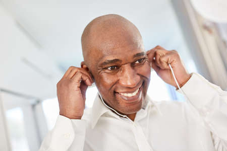 African man uses in-ear headphones in the home office for video conference