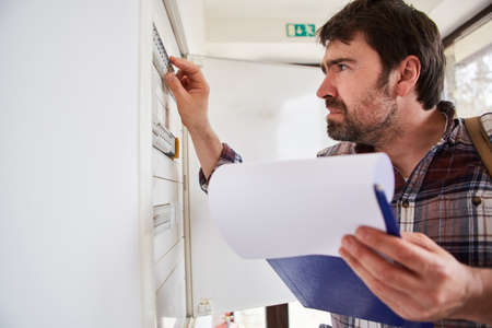 A specialist electrician checks the fuses in the distribution box with a checklistの写真素材
