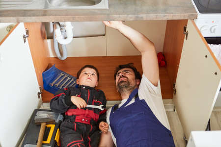 Father and son as a team of craftsmen repairing or installing a sink