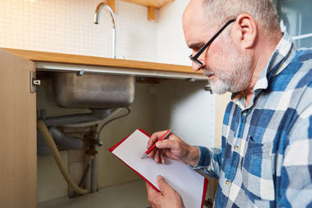 Craftsman in the kitchen writes checklist for repair service or estimateの写真素材