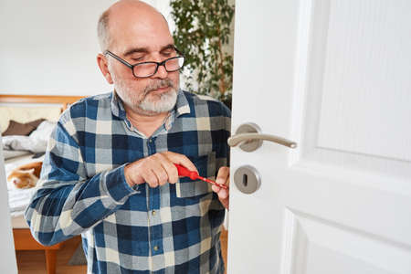 Man as handyman tradesman when changing door lock or repairing it at homeの写真素材