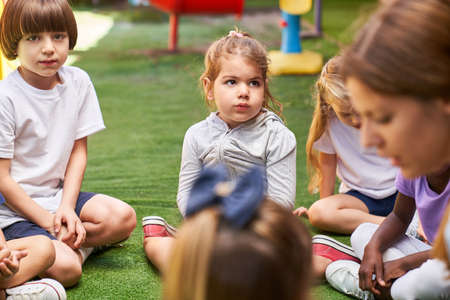Group of children and educator in conversation in kindergarten or day care center