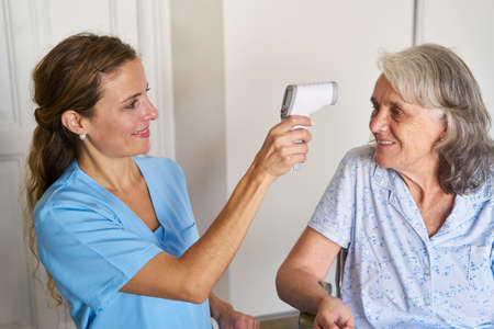 Nurse measuring a fever with a forehead thermometer in a senior citizen's home