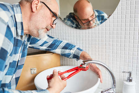 Handyman plumber repairs broken faucet on bathroom sink