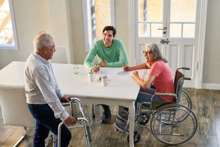 Son and senior parents with disabilities in assisted living or at the table in a retirement home
