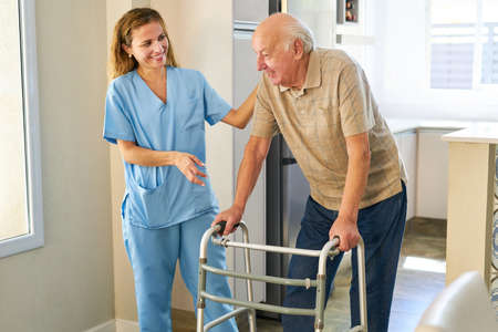 Friendly nurse helps senior with walker to go to rehab clinic or nursing home
