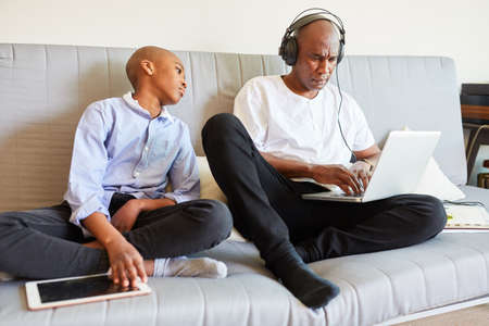 Curious child and man having a video conference with the laptop PC on the sofa in the home office