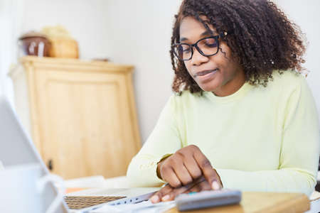 Business woman in the home office doing a calculation with the calculator on tax returnの写真素材