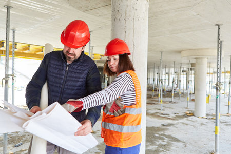 Craftsman and architect with construction plan together in the shell of the construction site of the house constructionの写真素材