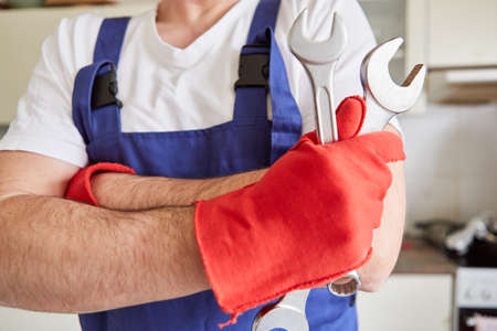 Handyman with two wrenches and red gloves