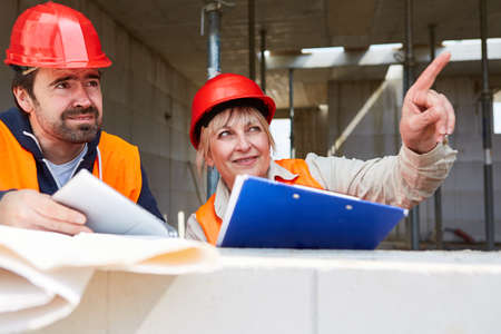 Architect with checklist on the building shell construction site gives an instruction to a...