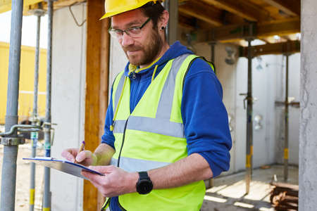 Craftsman building a house creates a cost estimate on a clipboard at the construction siteの写真素材