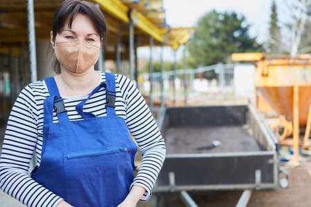 Woman as a construction worker or craftsman with protective mask on the construction site for occupational safetyの写真素材