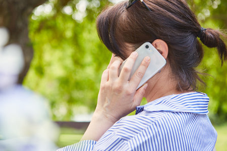 Business woman as a freelancer in the park in nature talking on the phone with the smartphoneの写真素材