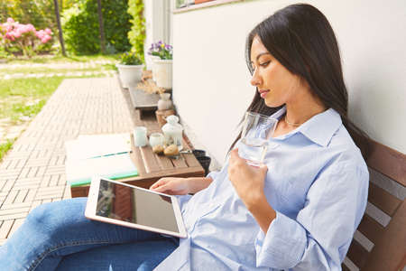Young business woman as a freelancer using tablet computer at home on the terraceの写真素材