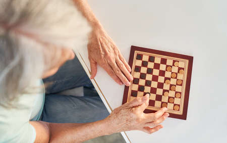 Senior woman playing checkers as a leisure activity or brain teaser in a retirement homeの写真素材