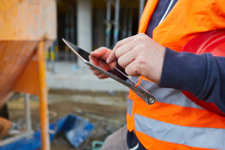 Craftsman or worker with tablet computer during construction planning on a construction site of house buildingの写真素材