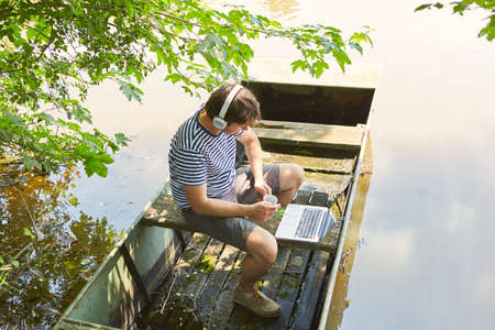 Man working on laptop computer online on summer vacation at the lake as a freelancerの写真素材