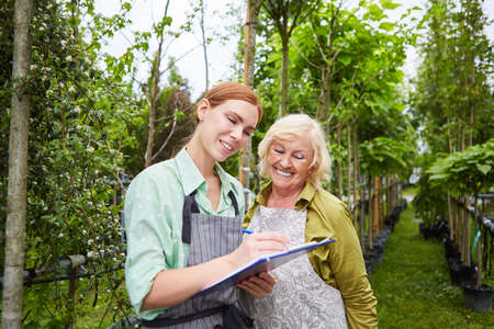 Nursery team with clipboard controls plant growth in nursery